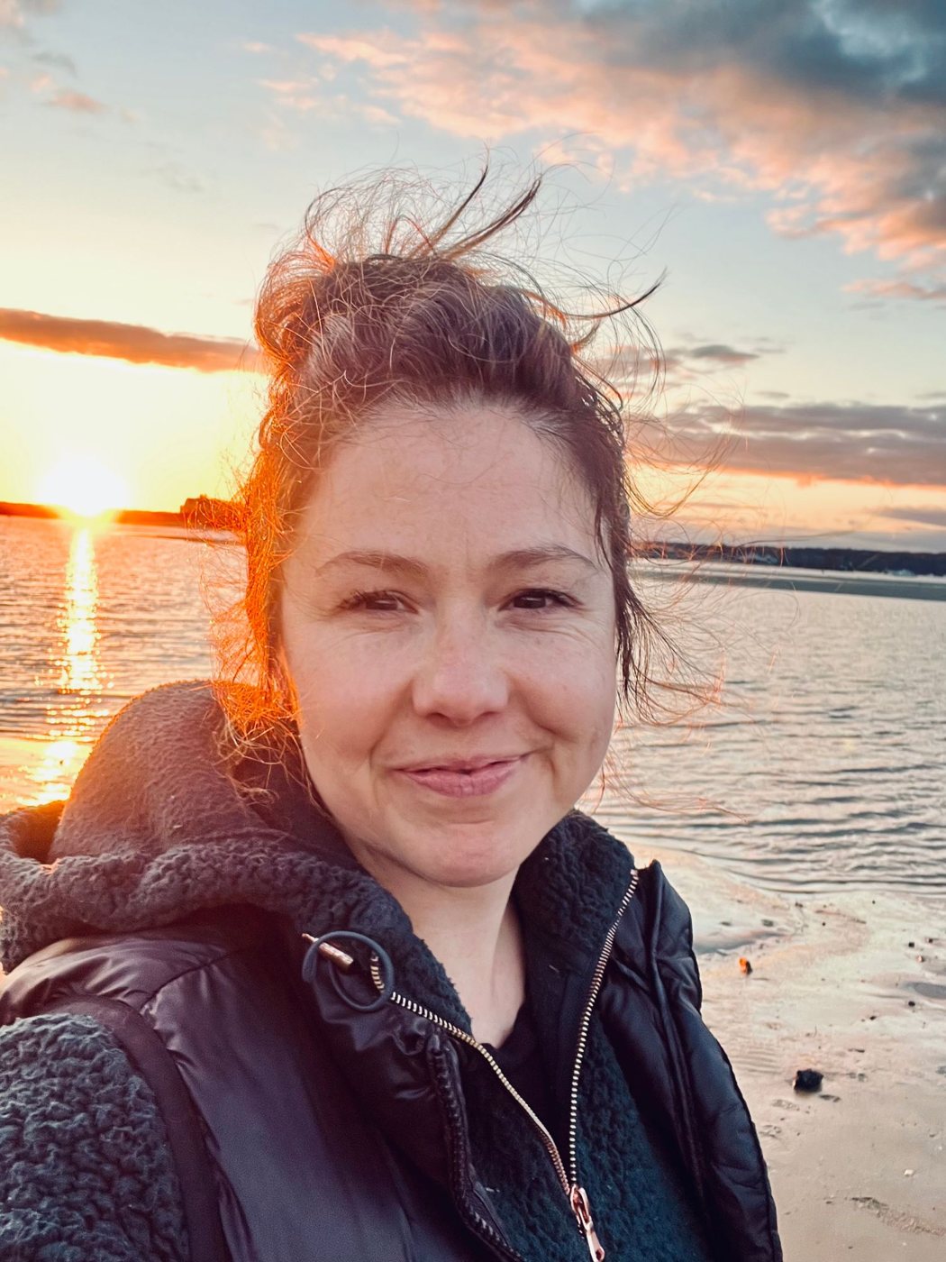 Dr. Stephanie Thrower smiling on a beach at sunset